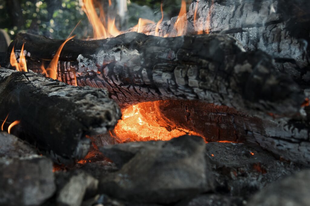 Close-up of a wood fire with vibrant flames engulfing charred logs.